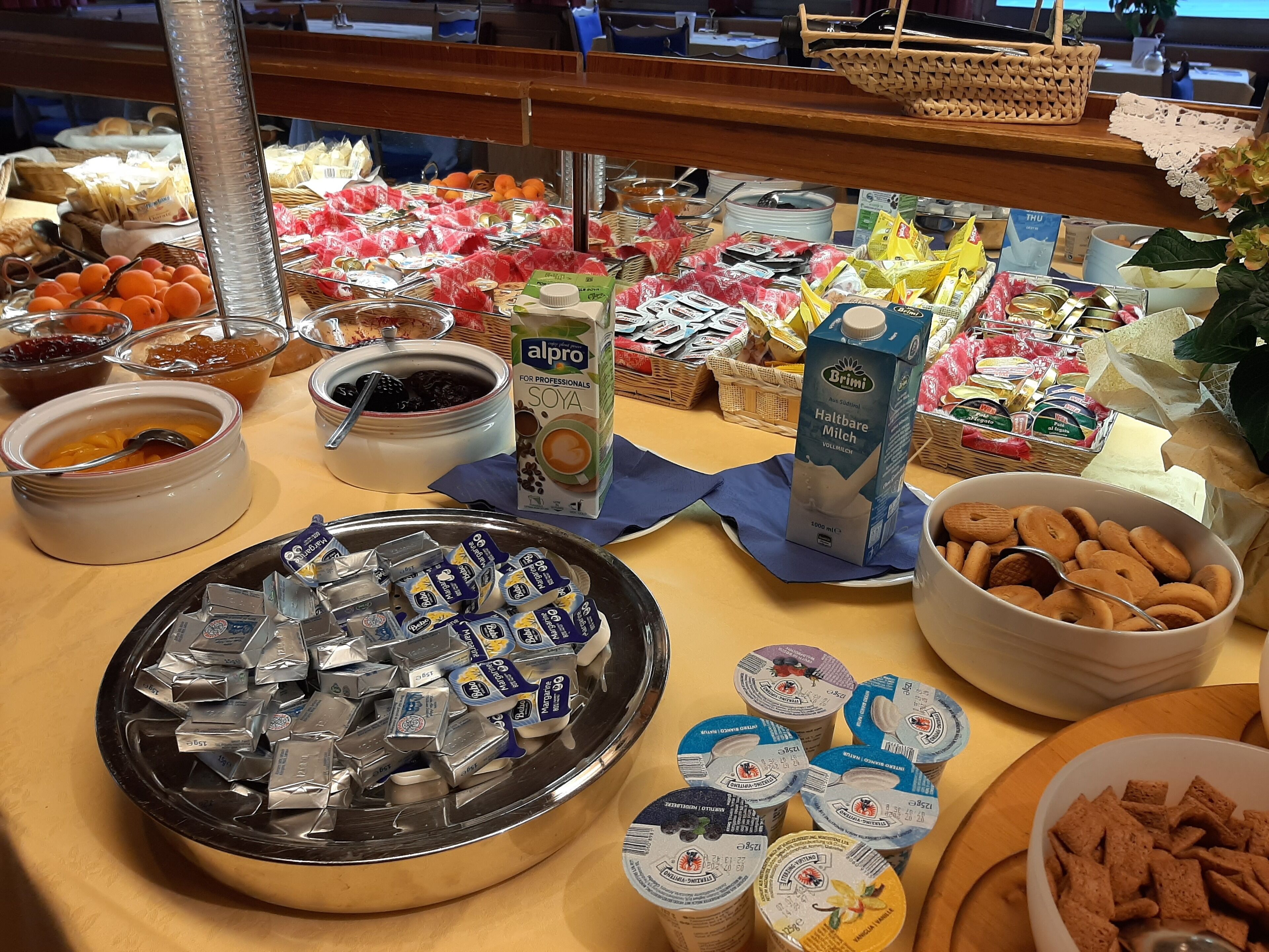 Een buffet met verschillende soorten eten, waaronder fruit, zuivelproducten en verpakte snacks.