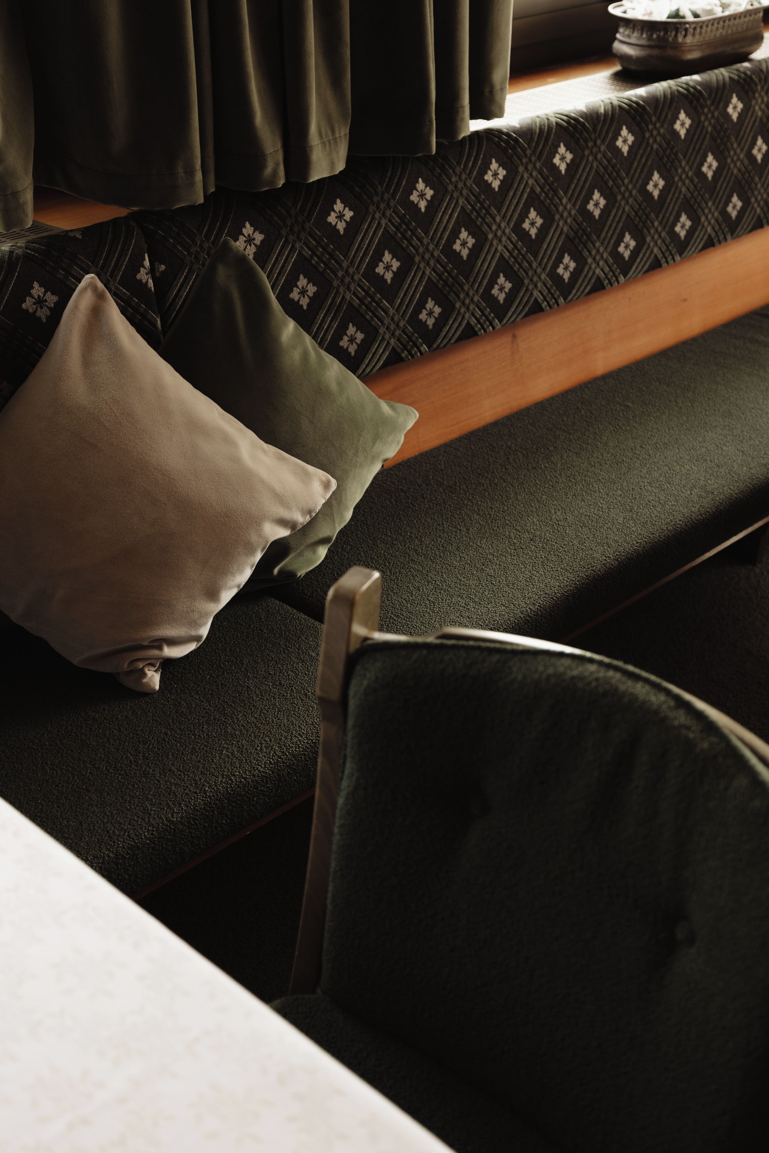A room with a bench, pillows, and a chair.