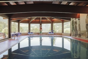 An indoor swimming pool with clear views of the surrounding landscape through large windows. - Hotel Rodes (Castelrotto)
