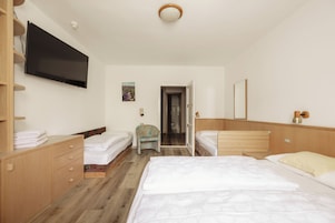 Una habitación de hotel con cama, una silla, un televisor y una puerta que da a un baño.