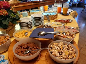 A breakfast buffet with various cereals, fruits, and beverages.
