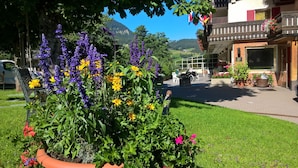 A hotel with a garden area featuring a variety of flowers and a view of the mountains. - Hotel Rodes (Castelrotto)