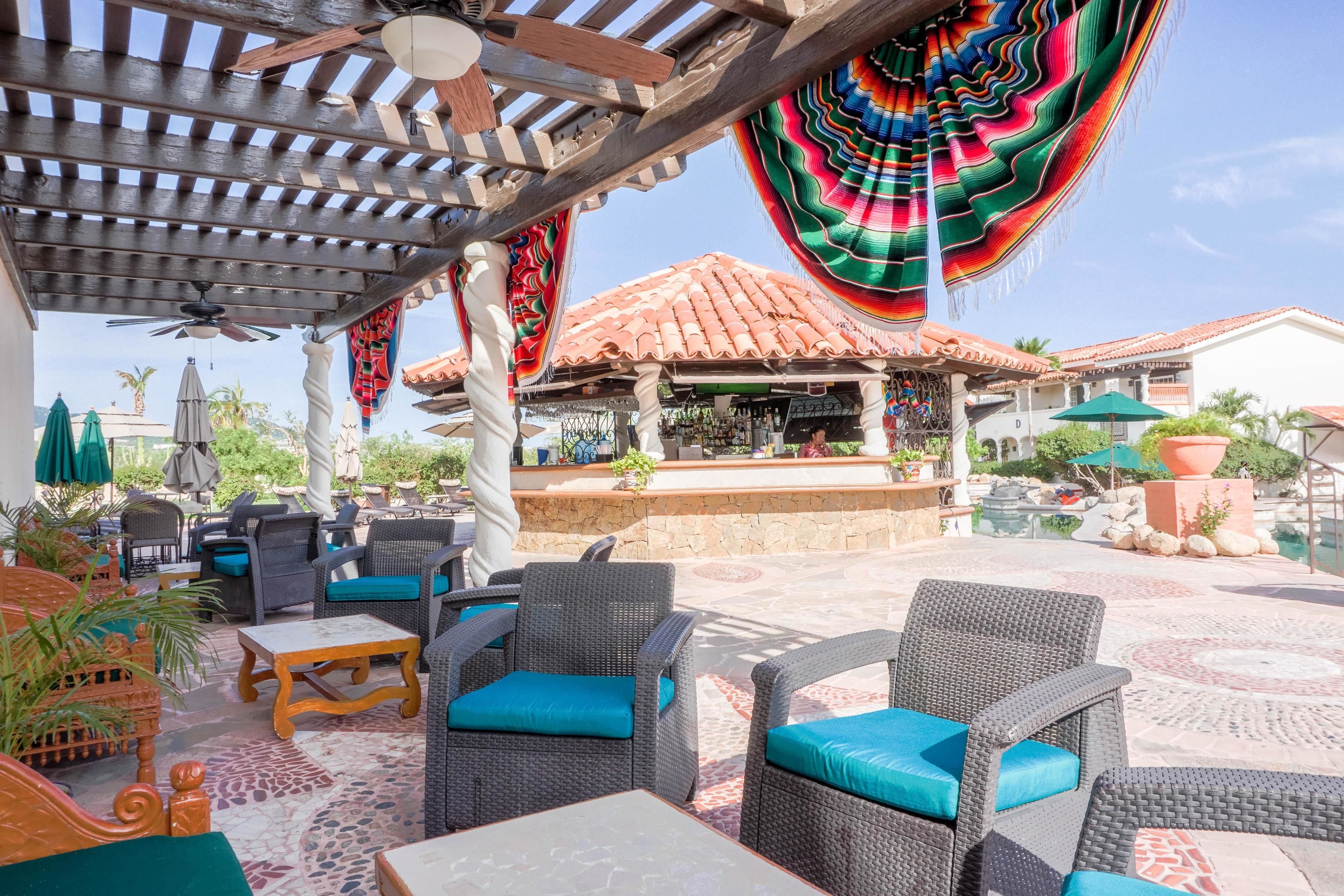 An outdoor patio area with wicker furniture, a bar, and a colorful woven canopy.