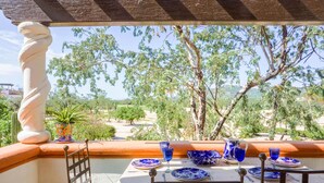 A terrace with a table set for dining, overlooking a scenic landscape with trees and hills. - 7BED Country Club 2 3 Bedroom Apartment By Senstay (Cabo San Lucas)