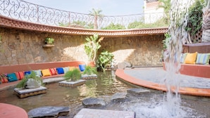 A courtyard with a water feature, stone walls, and colorful seating.