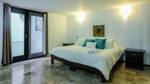 A bedroom with a bed, two bedside tables, a sliding glass door, and a painting on the wall. - PDC004 7 Bedroom Villa By Senstay (Playa del Carmen)