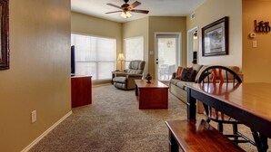 A living room with a ceiling fan, a wooden dining table, a sofa, and a chair. - Riverfront Bliss (New Braunfels)