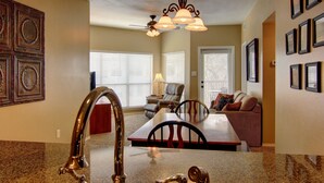 A kitchen with granite countertops, a stainless steel sink, and a chandelier. - Riverfront Bliss (New Braunfels)