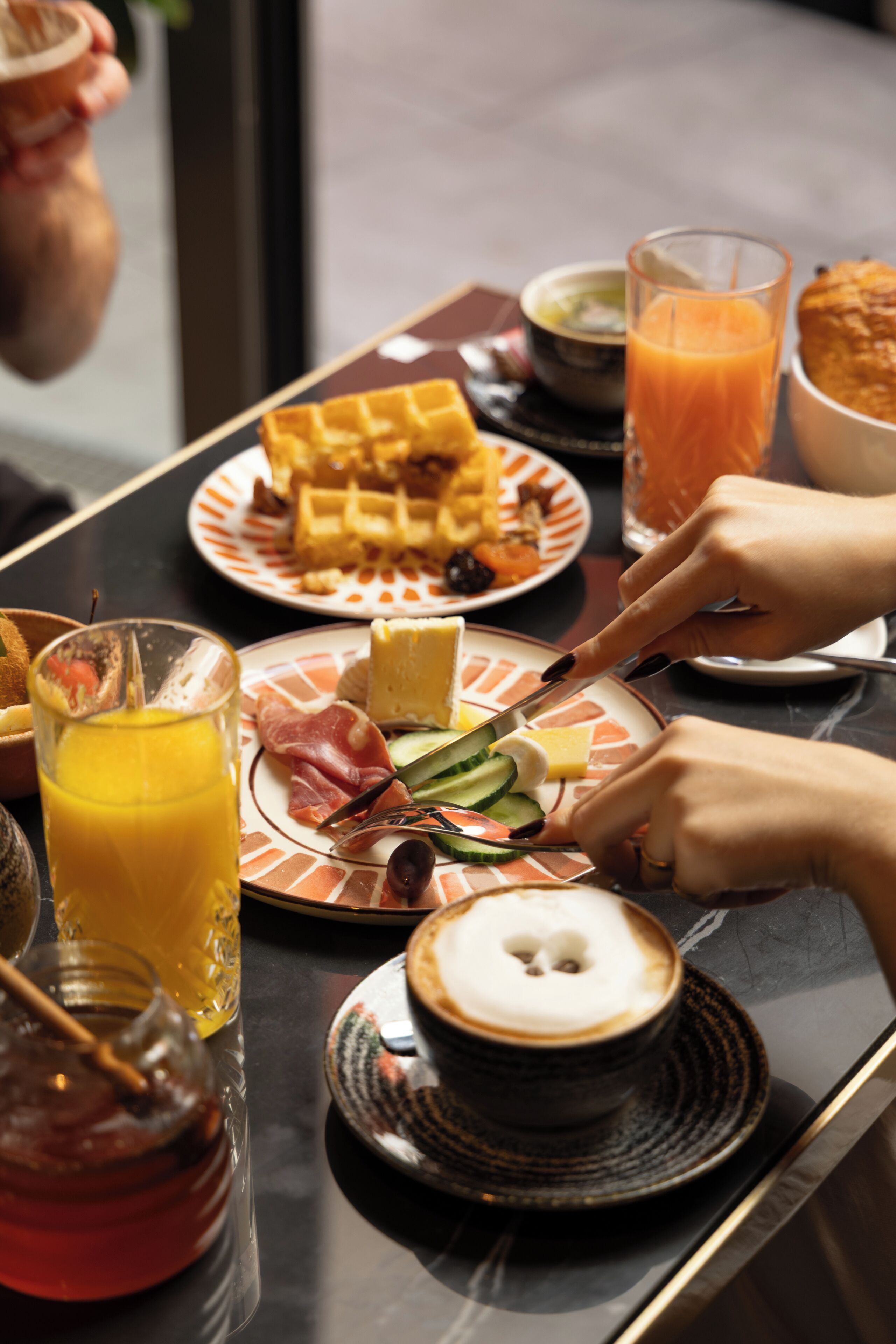 Mesa de café da manhã com diversos alimentos e um copo de suco de laranja.
