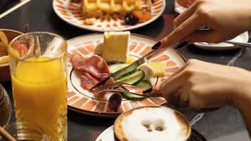 Mesa de café da manhã com diversos alimentos e um copo de suco de laranja.