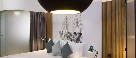 Una habitación de hotel moderna con una cama grande, un escritorio y un aplique grande montado en la pared.