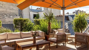 Une terrasse extérieure avec un canapé, des chaises, une table et des parasols.