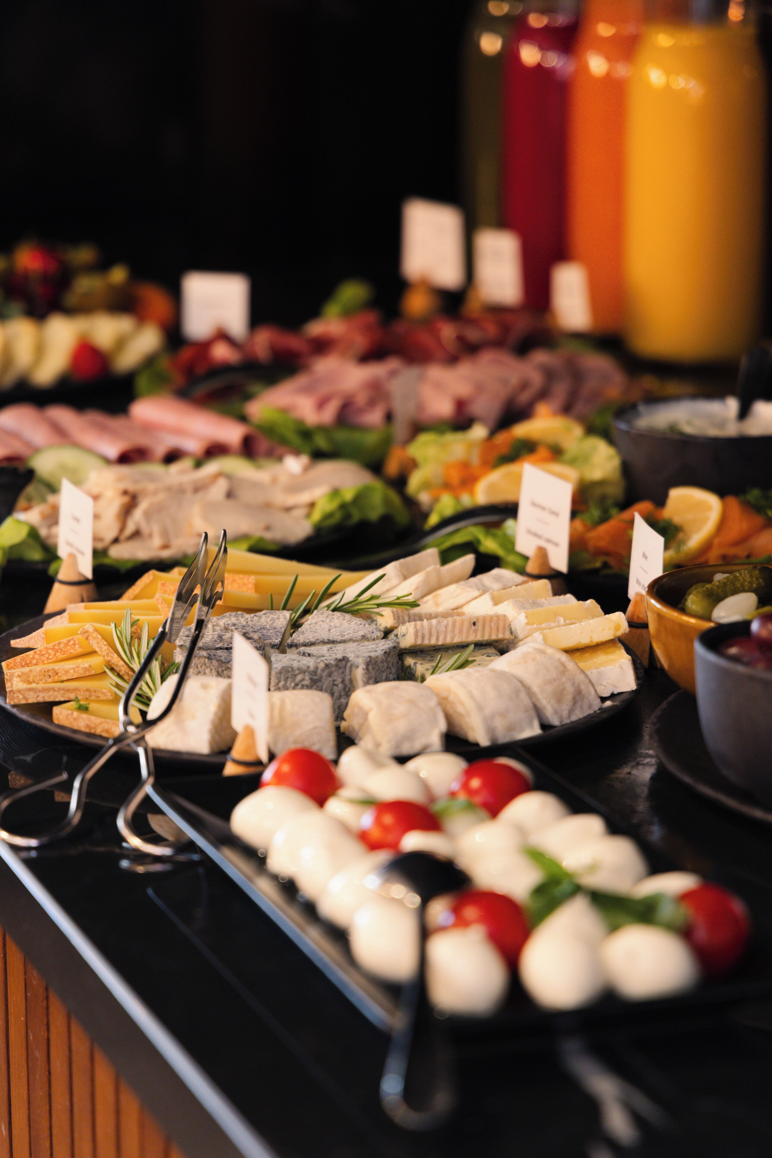 A buffet with various food items including cheeses, meats, and vegetables.