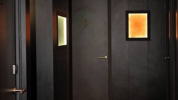 En hall med ett heltäckningsmatta på golvet, en dörr med ett litet fönster och en lampa i taket.