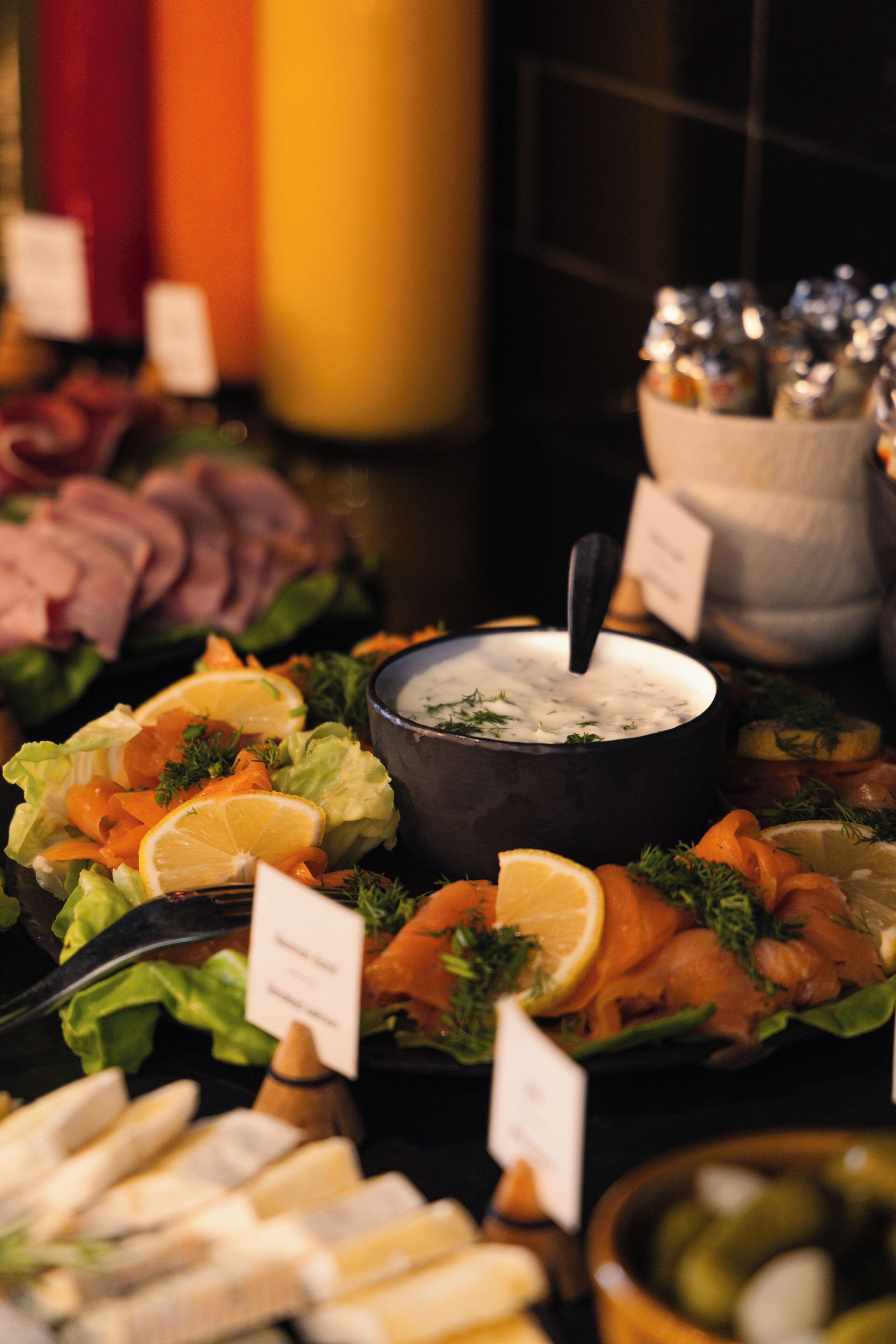 A buffet with various food items including sliced meats, vegetables, and a bowl of dip.