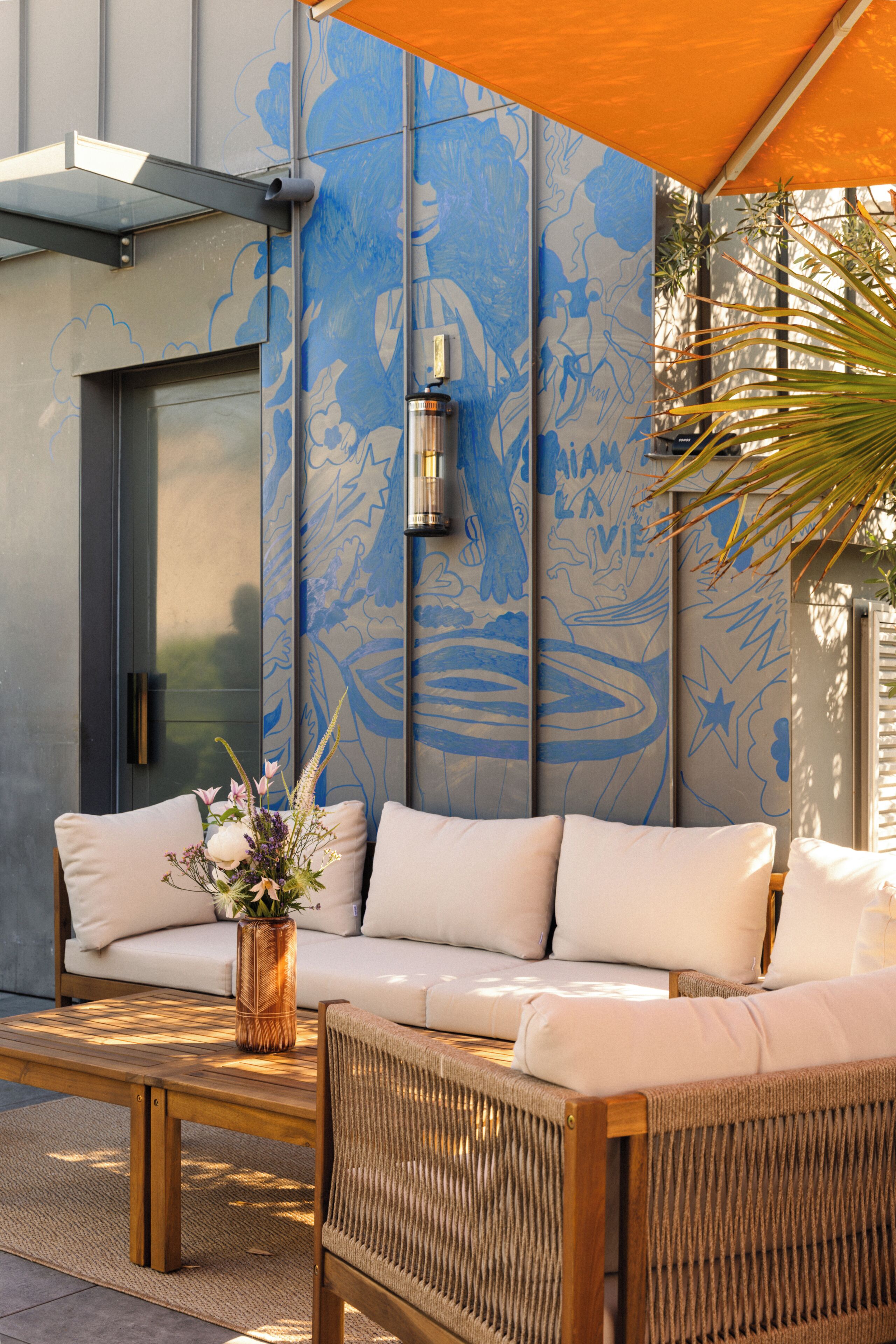 A modern outdoor seating area with a sofa, a wicker chair, and a wooden coffee table.