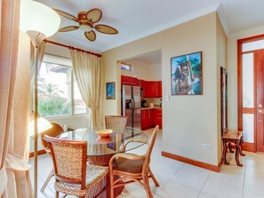 Enjoy a home-like atmosphere in this open-plan living space featuring a dining area with a glass-top table and wicker chairs.
