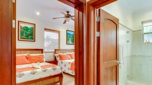 Quarto com duas camas, chuveiro e ventilador de teto.