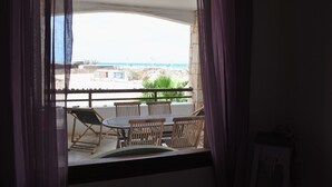 A balcony with a table and chairs, overlooking a coastal area with buildings and vegetation. - Sea View Apartments Boa Vista (Boa Vista)