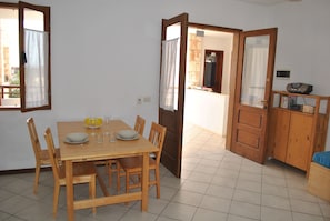 A dining area with a wooden table set for four, surrounded by chairs. There is a wooden cabinet with a radio on top. - Sea View Apartments Boa Vista (Boa Vista)