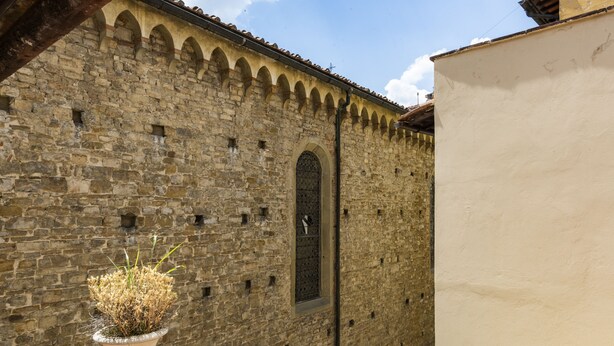 A stone building with a tiled roof, a window with a metal grille, and a potted plant in the foreground. - B&B San Remigio Firenze (Florence)