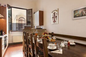 A dining area with a wooden table set for breakfast, including plates, cups, and a fruit bowl. - B&B San Remigio Firenze (Florence)