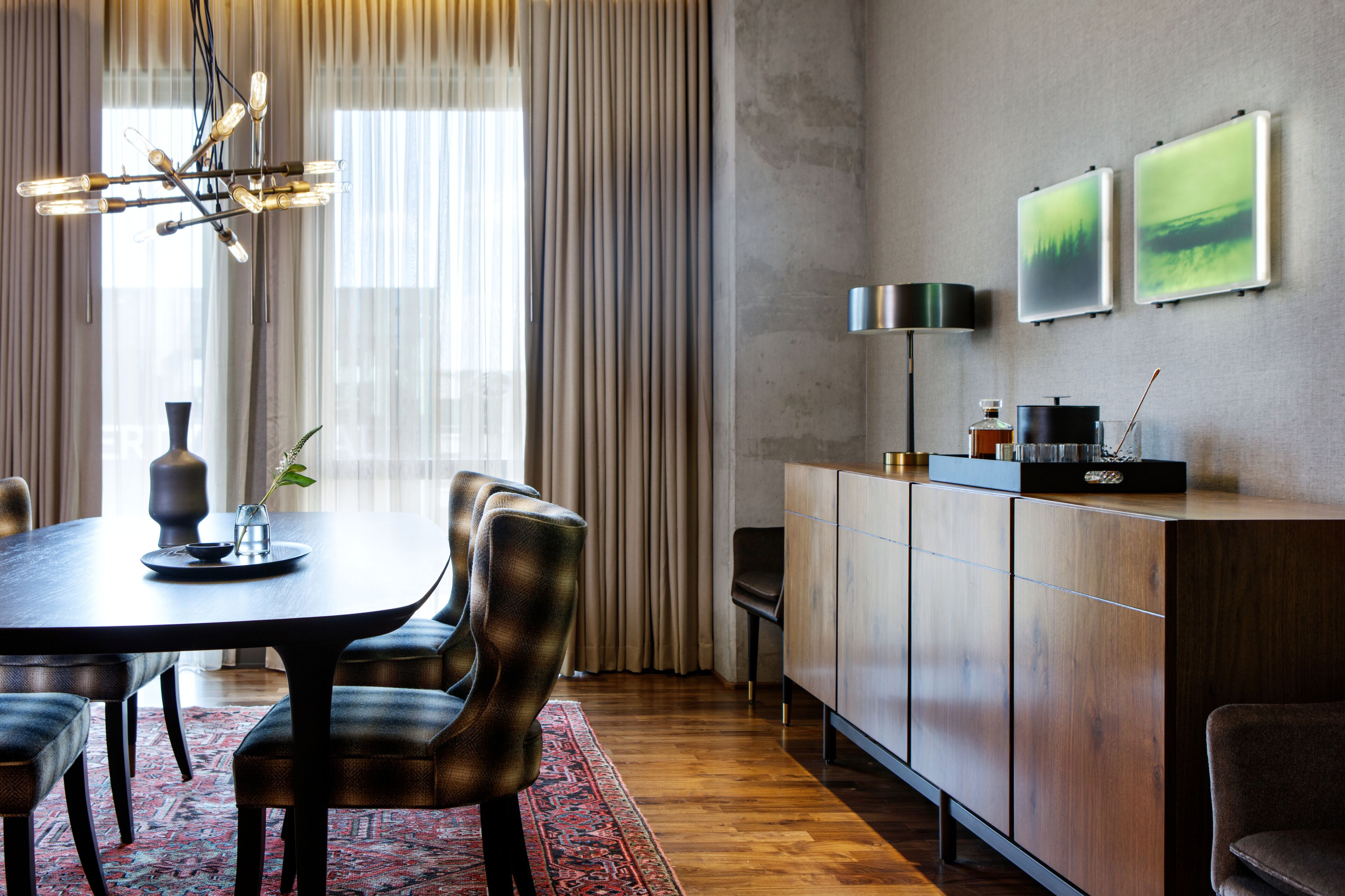 Un'area pranzo moderna con un tavolo in legno scuro, sedie imbottite e un tappeto decorato.