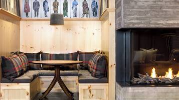 A cozy seating area with a fireplace, a table, and a wall with artwork.