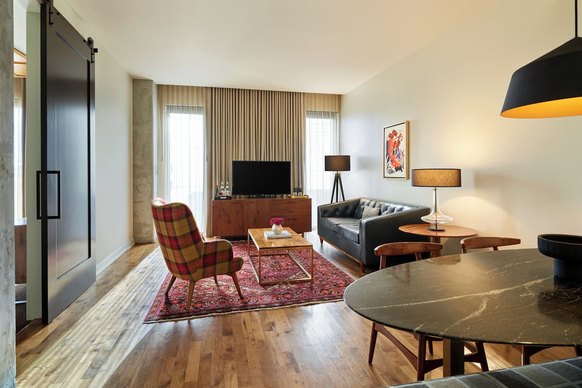 A modern living room with a flat-screen TV, a sofa, a dining table, and a coffee table.