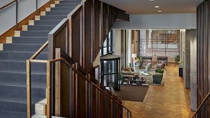 A modern interior with a staircase, wooden panel walls, and a dining area with a view. - Limelight Hotel Denver (Denver)
