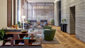 A spacious lobby with a modern design, featuring a large seating area with sofas and armchairs, a coffee table, and a fireplace. - Limelight Hotel Denver (Denver)