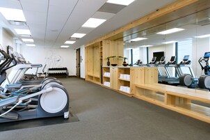 A gym with multiple treadmills, exercise bikes, and a mirrored wall.