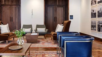 A modern living room with a wooden floor, a coffee table, two sofas, and a blue chair.