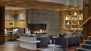 A modern living room with a fireplace, wooden shelves, and a staircase. - Limelight Hotel Denver (Denver)