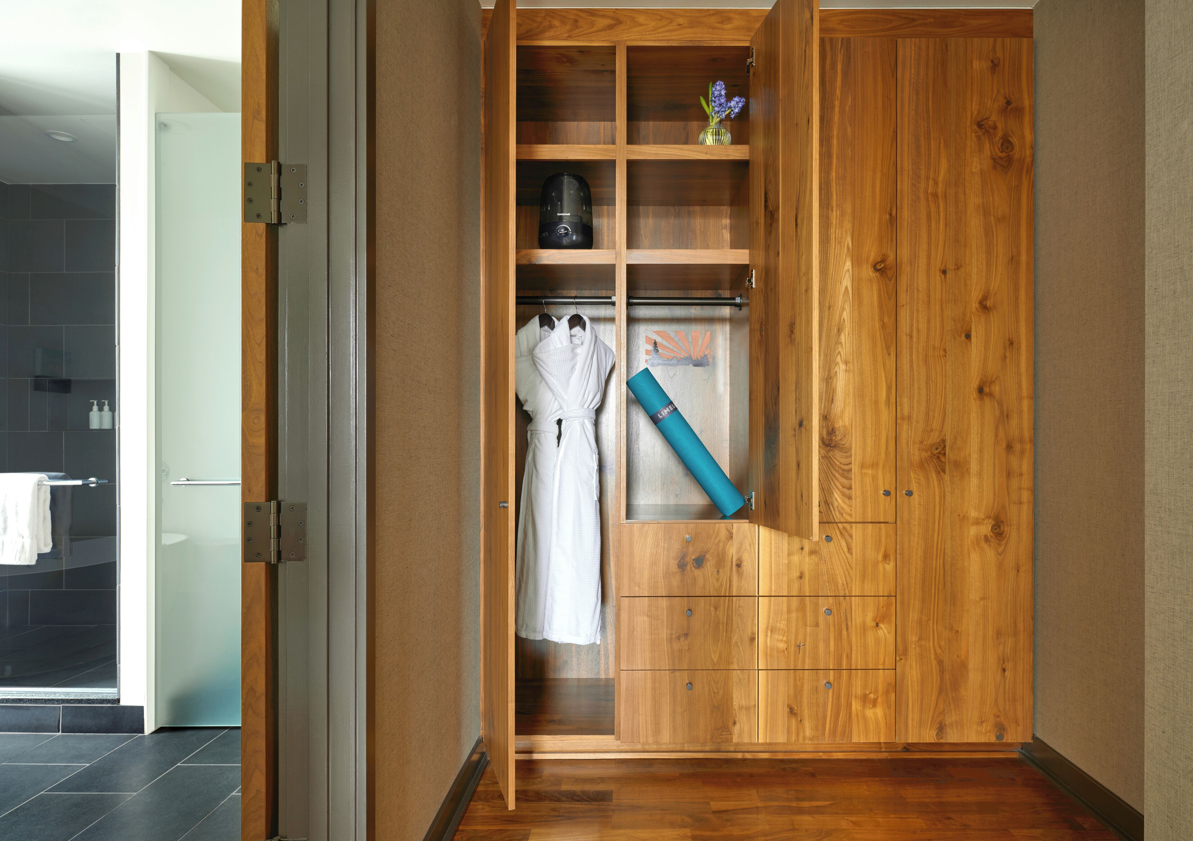 Um guarda-roupa de madeira com vários compartimentos, uma barra para pendurar roupas e uma pequena prateleira com um vaso.