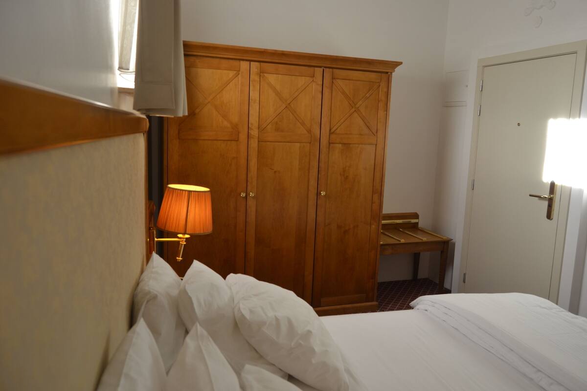 Een hotelkamer met een bed, een houten garderobe, een lamp en een bank.