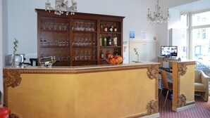 Eine Barbereich mit einem Holzkabinett, gefüllt mit Flaschen und Gläsern, einer Obstschale und einem Fernseher auf einem Schrank.