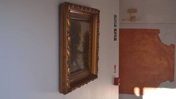 A framed artwork on a wall, a light switch, and a partially visible textured wall.
