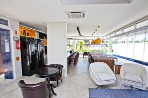 A modern kitchen with black appliances, a dining area with a wooden table and chairs, and large windows offering a view of the outdoors.