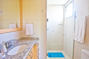 A bathroom with a granite countertop sink, a mirror, and a shower with a glass door. - FL014 3 Bedroom Apartment By Senstay (Florianópolis)