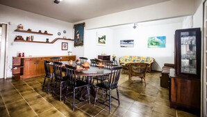 A dining area with a round table and chairs, a sofa, and a cabinet with shelves. - FL023 6 Bedroom Holiday home By Senstay (Florianópolis)