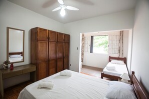 A bedroom with a large wardrobe, a bed with white linens, a bedside table, and a window with curtains. - FL023 6 Bedroom Holiday home By Senstay (Florianópolis)