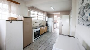 A compact kitchen with basic appliances, a tiled floor, and a window with blinds. - FL023 6 Bedroom Holiday home By Senstay (Florianópolis)