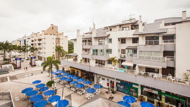A multi-story hotel with balconies, outdoor seating with umbrellas, and a pedestrian walkway.