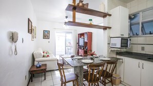 A compact kitchen with white cabinets, a microwave, and a dining area with a table set for two.