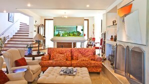 A spacious living room with a large fish tank, a sofa, and a fireplace. - FL004 5 Bedroom Villa By Senstay (Florianópolis)