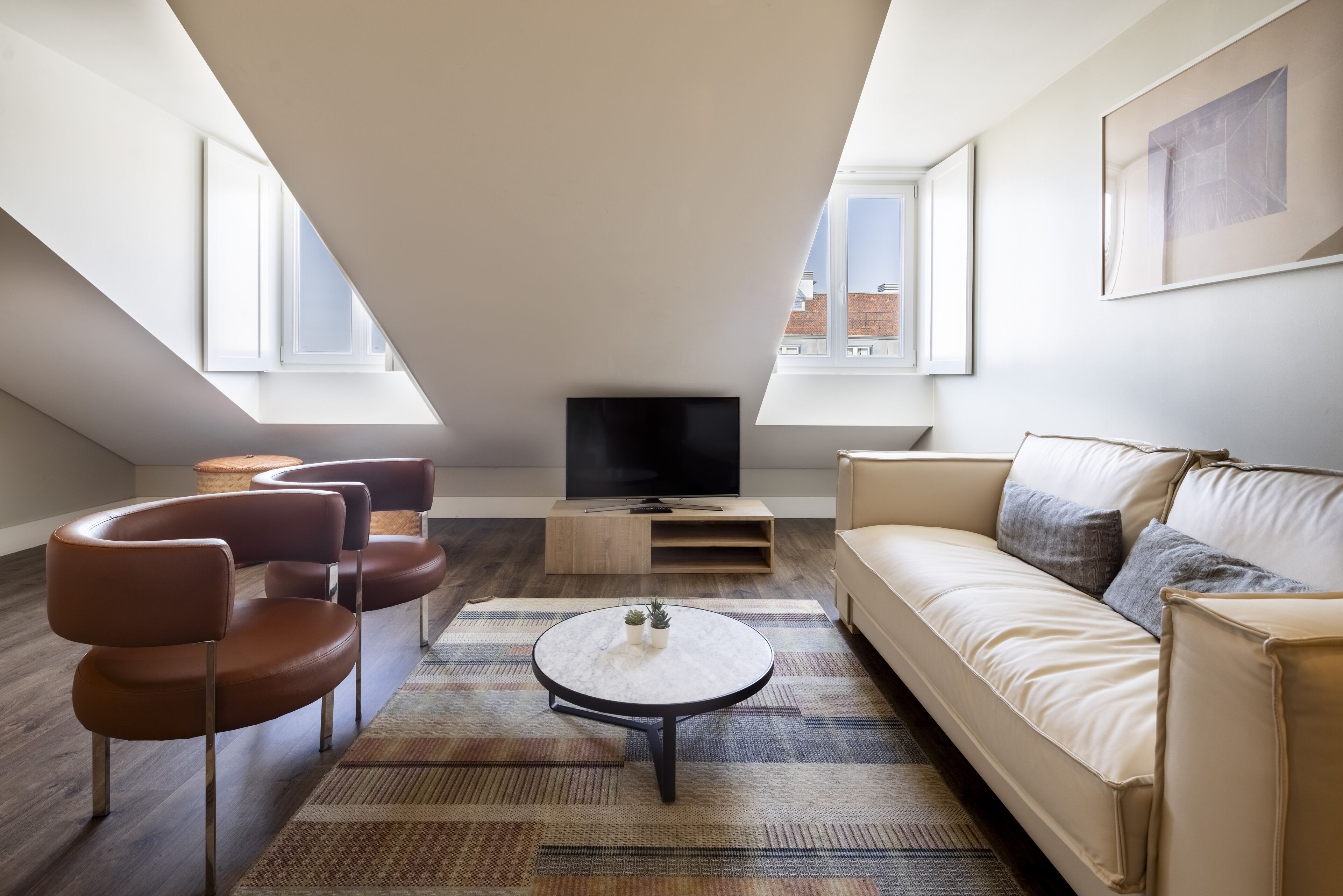 A modern living room with a sofa, chairs, a coffee table, and a TV.