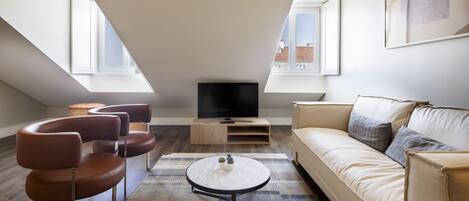 A modern living room with a sofa, chairs, a coffee table, and a TV.