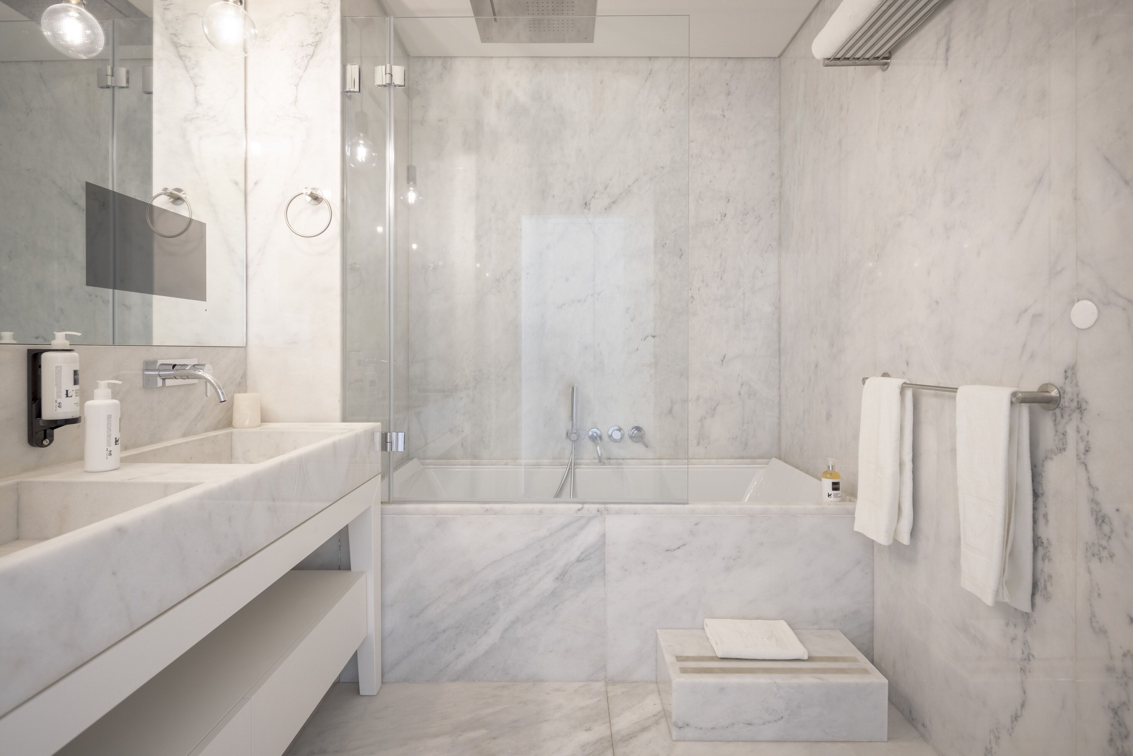 Ein modernes Badezimmer mit einem großen Spiegel, zwei Waschbecken, einer Dusche und einem Handtuchhalter.