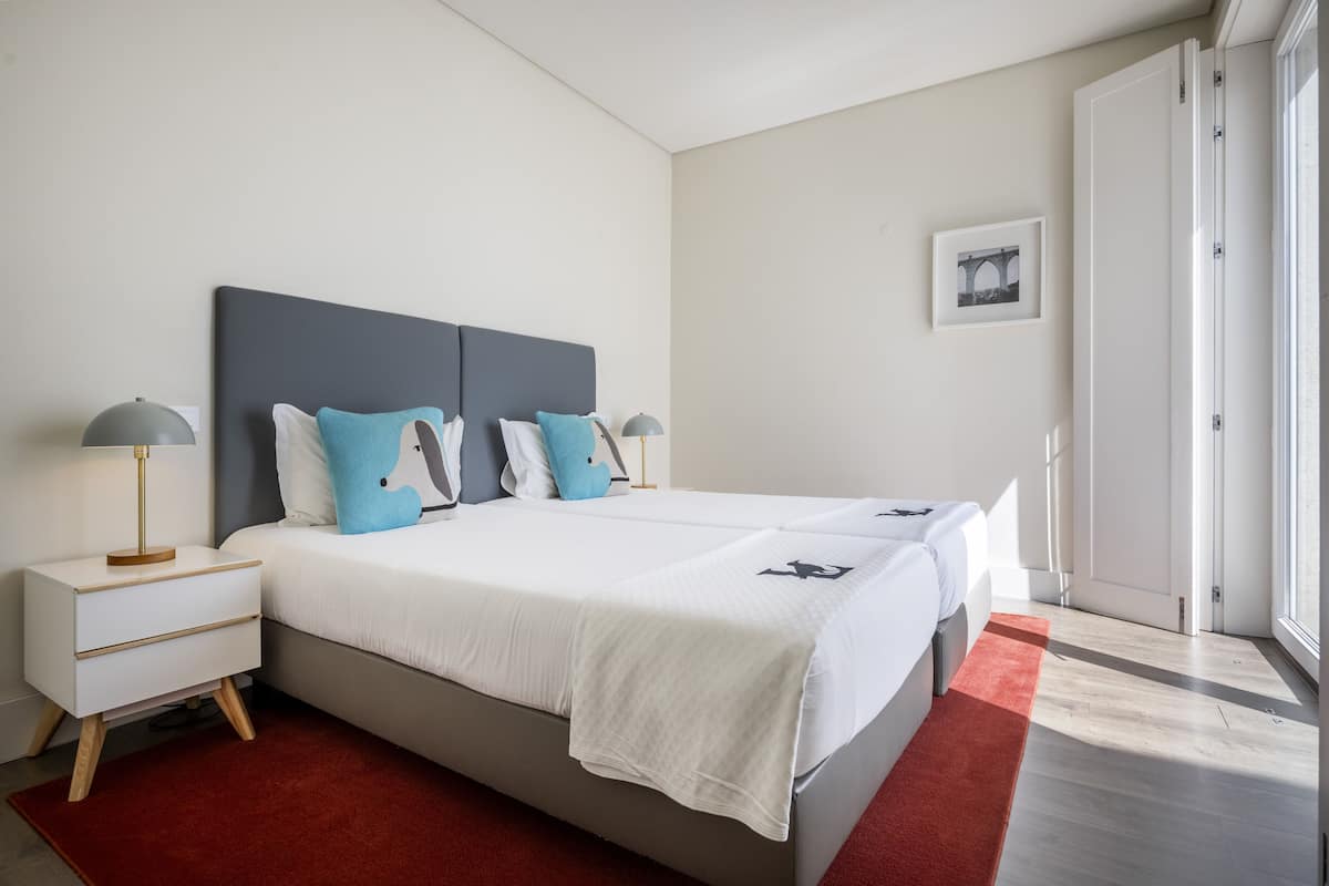 Ein modernes Schlafzimmer mit einem großen Bett, Nachttischen und einem roten Teppich.
